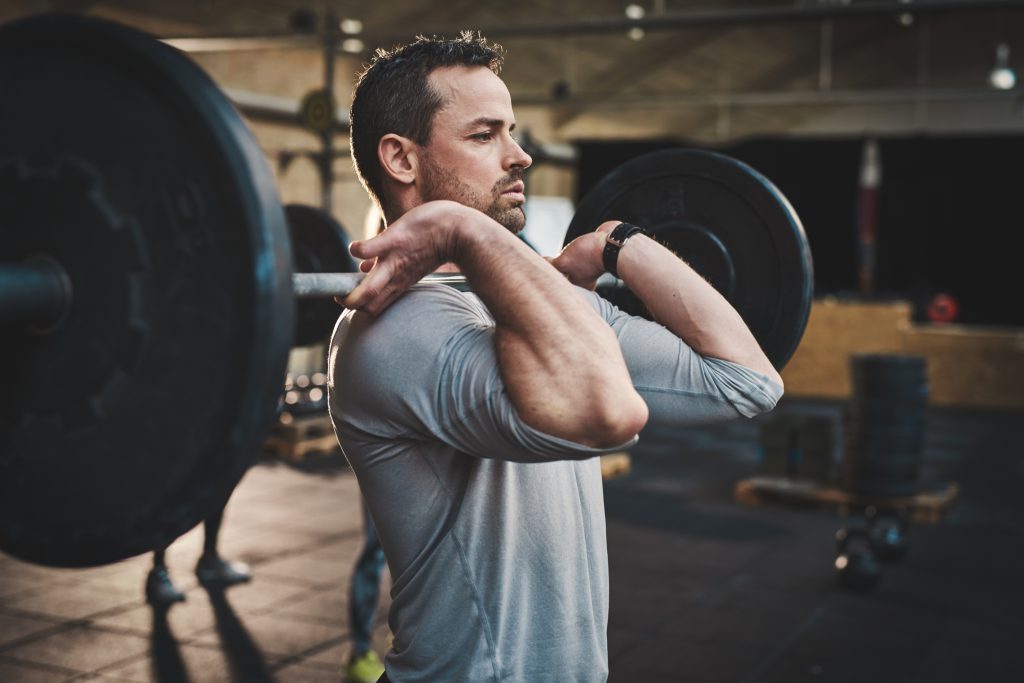 Man pulling up large barbell in fitness class