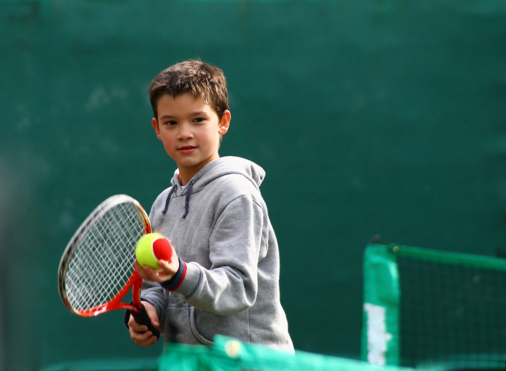 Little tennis player on a blurred green backround
