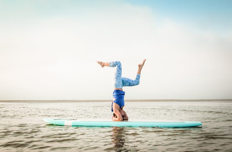 A woman practices yoga on a paddleboard