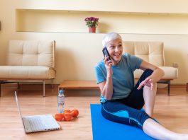 Senior woman using smartphone at home after exercise
